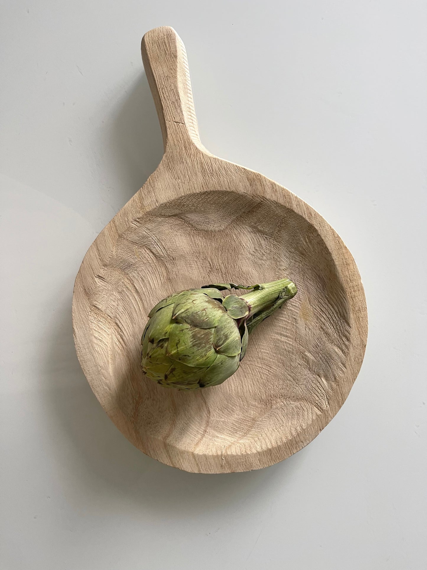 This hand-carved tray is made of 100% Paulownia wood. This wooden tray is round with a handle, which creates a natural and boho-chic style. This tray can be used in a variety of ways. The tray can be used as display area on a coffee table, holding fresh fruits and vegetables in the kitchen, or as a serving piece for a special occasion. Dimensions: 13-1/2"L x 9"W