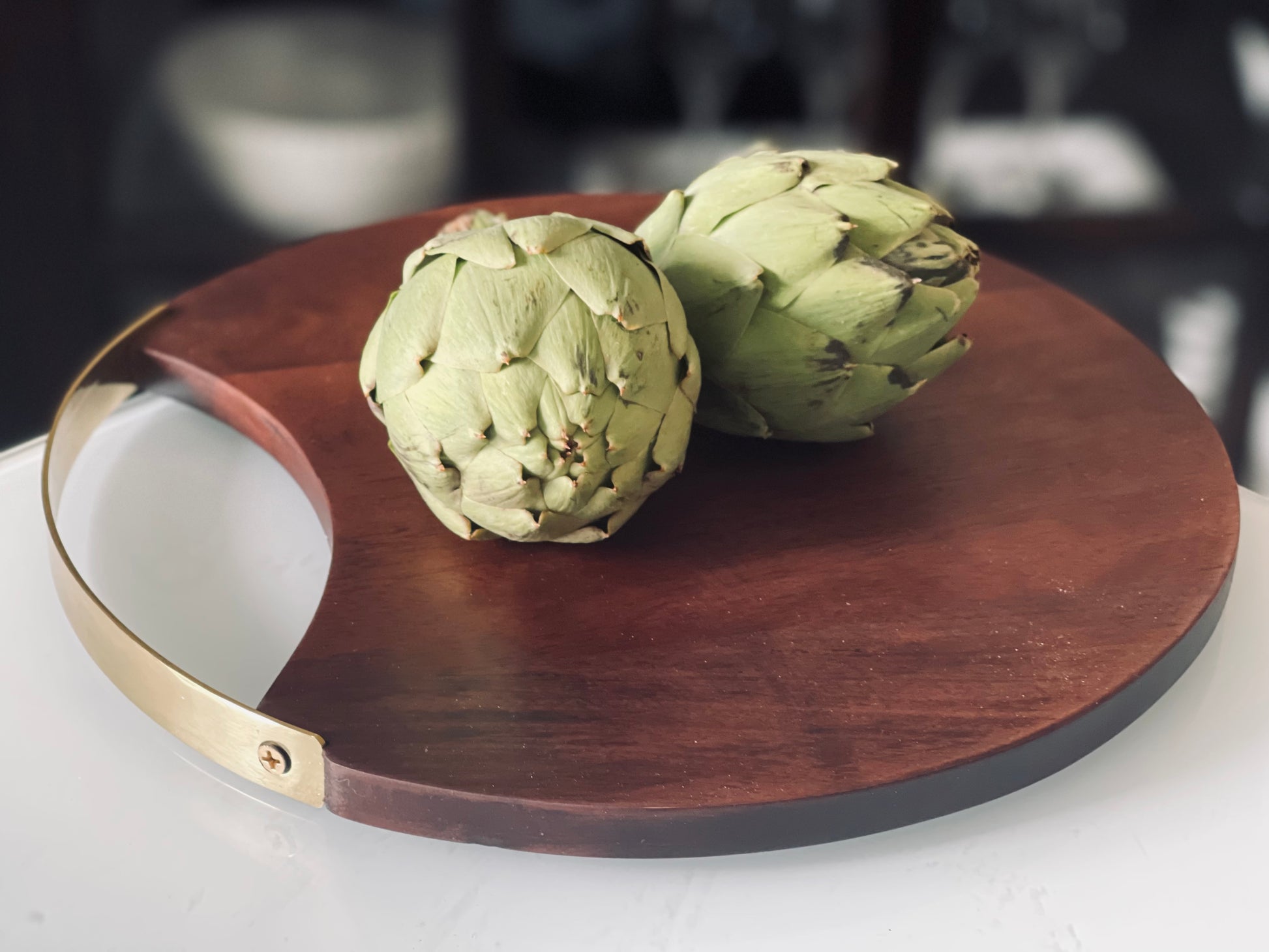 Round wood board with brass handle Perfect for serving cheeses and appetizers Designed with elegance for a timeless trend Made with high-quality wood and brass Dimension: 12" in diameter Material(s): wood